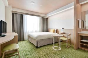 大津町にあるベッセルホテル熊本空港のベッド、テーブル、椅子が備わるホテルルームです。