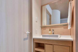 a bathroom with a sink and a mirror at Vessel Hotel Kumamoto Airport in Ozu