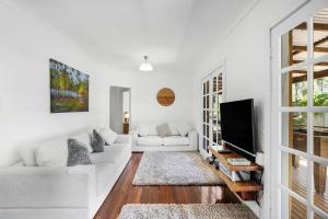a white living room with a white couch and a tv at Nannup Bush Retreat in Nannup