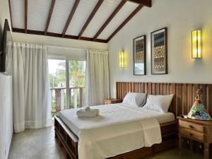 ein Schlafzimmer mit einem großen Bett und einem Fenster in der Unterkunft Casa Canoa Hotel Boutique à Beira-mar com Piscina e Café da manhã in Guarujá