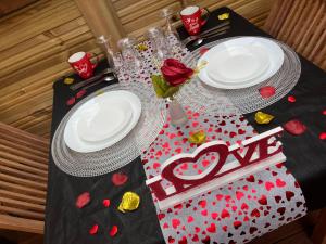 una mesa con dos platos y un signo de amor en ella en Les chalets de Marie et Stéph - Jacuzzi SPA Privatif sans vis à vis , vue mer, en Saint-Denis