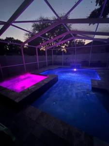 a lit up swimming pool at night with purple lights at Pink Sunshine: Private Heated Pool and Spa, Close to Beach in Largo