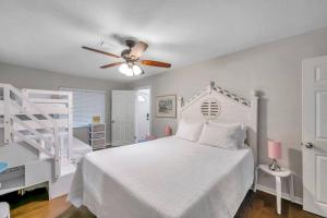 a bedroom with a white bed with a ceiling fan at Pink Sunshine: Private Heated Pool and Spa, Close to Beach in Largo
