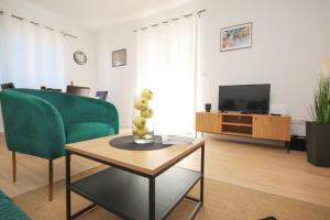 sala de estar con sofá verde y TV en Apartments Mira en Cavtat