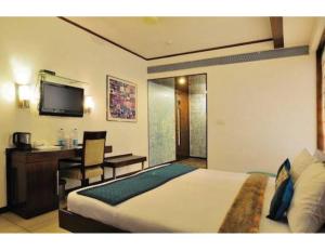 a bedroom with a bed and a desk and a television at Hotel The Tulip ,Chandigarh in Chandīgarh