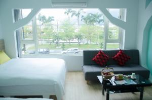 a bedroom with a bed and a couch and a window at 蘋果樹民宿 - 花蓮火車站住宿有電梯附停車場 in Hualien City