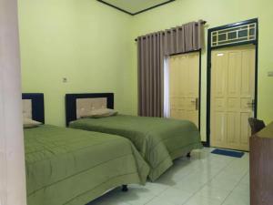 a bedroom with two green beds and a door at Lembah Rinjani Villa & Resto by ecommerceloka in Sembalun Lawang