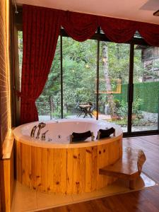 a large wooden tub in a room with a large window at Esinti Bungalows Otel in Çamlıhemşin