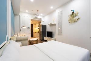 a bedroom with a white bed and a living room at Olala Saigon Apartment - Rivergate Residence in Ho Chi Minh City