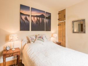 a bedroom with a white bed with three paintings on the wall at 3 bed in Ullock SZ043 in Arlecdon