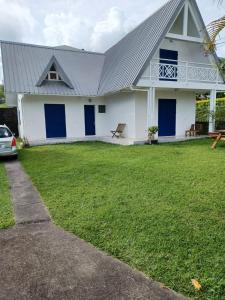 een wit huis met blauwe deuren en een grasveld bij Villa Nicky in Le Tampon