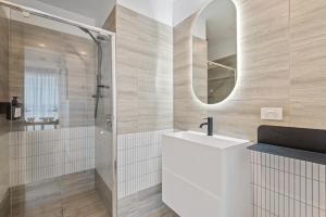 uma casa de banho com um lavatório branco e um espelho. em Elegant Collingwood Apartment with City Views em Melbourne