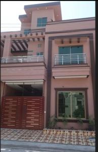ein rosafarbenes Haus mit einem Tor und einem Balkon in der Unterkunft 5-Bedroom Vacation Home in Lahore