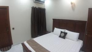 Schlafzimmer mit einem Bett mit weißer Bettwäsche und Kissen in der Unterkunft 5-Bedroom Vacation Home in Lahore