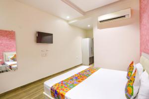 um quarto com uma cama e uma televisão na parede em FabHotel Uday Villa em Kanpur