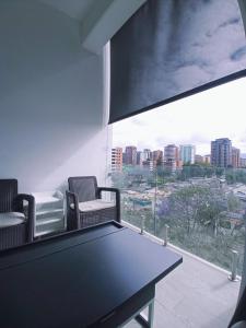 una sala de conferencias con mesa, sillas y ventana en APARTAMENTO CON TERRAZA CERCA DEL AEROPUERTO, en Guatemala