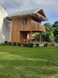 a wooden house with a thatched roof on a field at Brigitte´s Rental House in Dauin