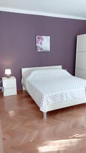 1 dormitorio con cama blanca y pared morada en Relax, en Preko