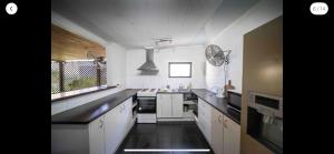 a kitchen with white cabinets and a black floor at Grimshaw House in Cairns