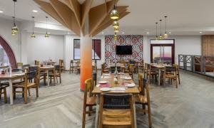 a dining room with tables and chairs and a tv at Ginger Durgapur in Durgāpur