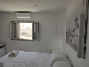 a white bedroom with a bed and a window at Central Santorini Serenity Rooms in Fira