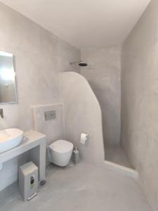 a white bathroom with a sink and a toilet at Central Santorini Serenity Rooms in Fira