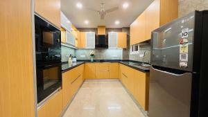 a kitchen with yellow cabinets and a stainless steel refrigerator at Olive Service Apartments Saket in New Delhi