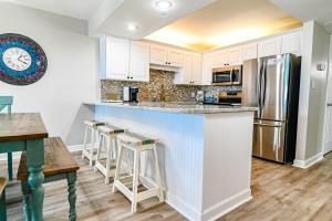 a kitchen with white cabinets and a counter with bar stools at Direct Oceanfront Magic at Sea Marsh w Pool in Myrtle Beach