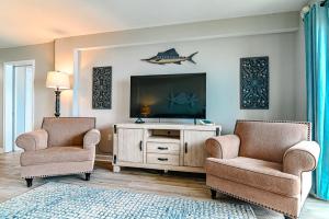 a living room with two chairs and a flat screen tv at Direct Oceanfront Magic at Sea Marsh w Pool in Myrtle Beach +41 photos