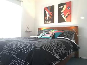 a bedroom with a black and white bed with pillows at Geelong Delight: Embrace Comfort @ Braund Avenue in Norlane
