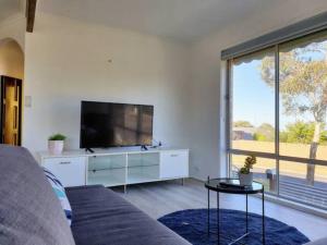 een woonkamer met een flatscreen-tv en een bank bij Geelong Delight: Embrace Comfort @ Braund Avenue in Norlane