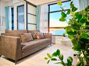 sala de estar con sofá y ventana grande en #10 Jesselton Quay City Pads Seaview by Zeluxo en Kota Kinabalu