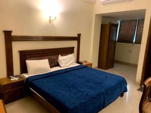 a bedroom with a bed with a blue comforter at Hotel Suncity & Restaurant in Hisār