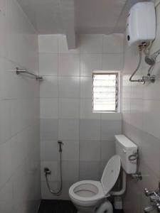 a white bathroom with a toilet and a window at 1bhk flat Bandra in Mumbai