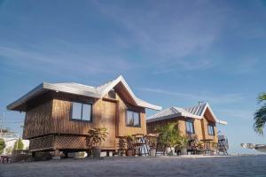 a wooden house with tables and chairs in front of it at The Blessed Purple Bamboo Beach Resort in Alaminos