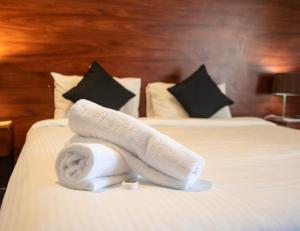 ベルモントにあるBelmont Hotel Lake Macquarieのホテルのベッドの上にタオルを積み重ねる