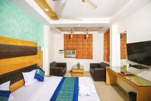 um quarto com uma cama, uma secretária e uma televisão em Hotel Lav-Kush em Nova Deli
