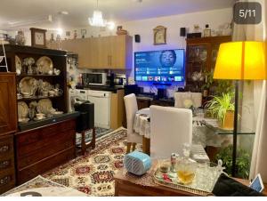 a living room with a table and a kitchen with a tv at Room in zone 2 in London