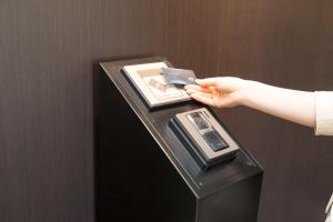 a person holding a cell phone in an atm machine at Sanco Inn Nagoya Fushimi in Nagoya