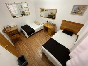 Habitación pequeña con 2 camas y espejo. en Hostal Roma Condesa en Ciudad de México