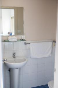 Baño blanco con lavabo y espejo en Belmont Hotel Lake Macquarie en Belmont