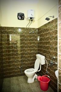 a bathroom with a toilet and a shower and a bucket at Queen's Residency in Guwahati