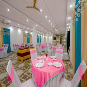 une chambre avec des tables et des chaises roses et blanches dans l'établissement Hotel Roop, à Sundarnagar