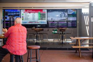 um homem parado em frente a um bar com monitores em Belmont Hotel Lake Macquarie em Belmont