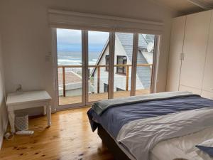 a bedroom with a bed and a view of the ocean at MakiSaki Beach House in Herolds Bay