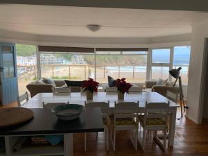 a living room with a dining room table with a view of the ocean at MakiSaki Beach House in Herolds Bay