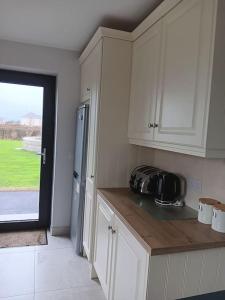 a kitchen with white cabinets and a door to a yard at Duplex/2 Bedrooms on Kildare/Carlow/Laois Border in Carlow