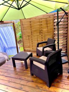 eine Terrasse mit 2 Stühlen und einem Sonnenschirm in der Unterkunft Lodge Agapë in Le Tampon
