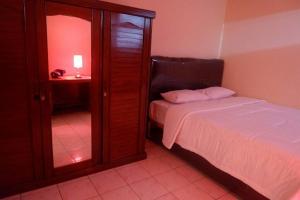 - une chambre avec un lit à côté d'un miroir dans l'établissement Villa Enos by GroRental, à Genteng