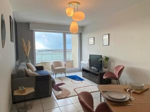 een woonkamer met een bank en een tv bij Front de mer vue exceptionnelle in Granville